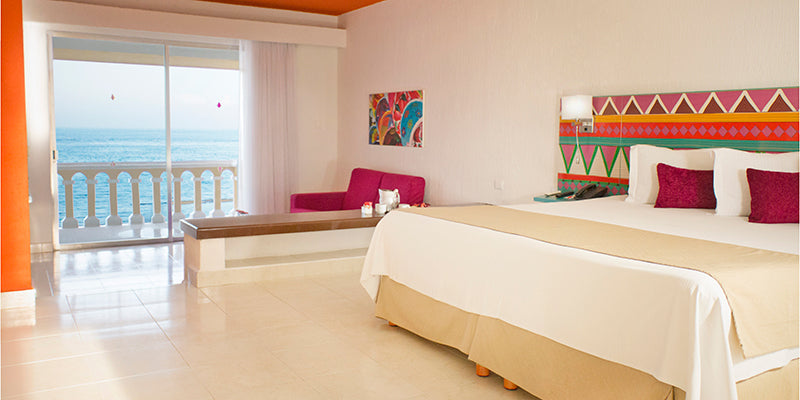 Well-appointed guest room at All Ritmo Resort with modern decor and a balcony overlooking the ocean.